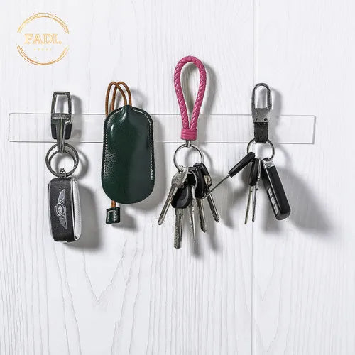 Nano double-sided tape in use — keys and keychains hanging from tape strips stuck on a white wood-paneled wall