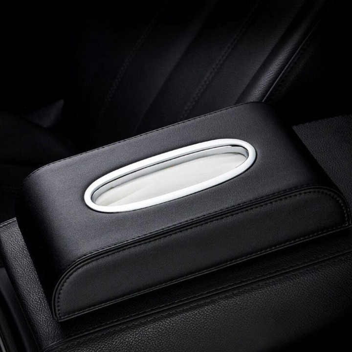 Black PU leather tissue box holder on a car armrest — oval chrome-trimmed dispensing opening