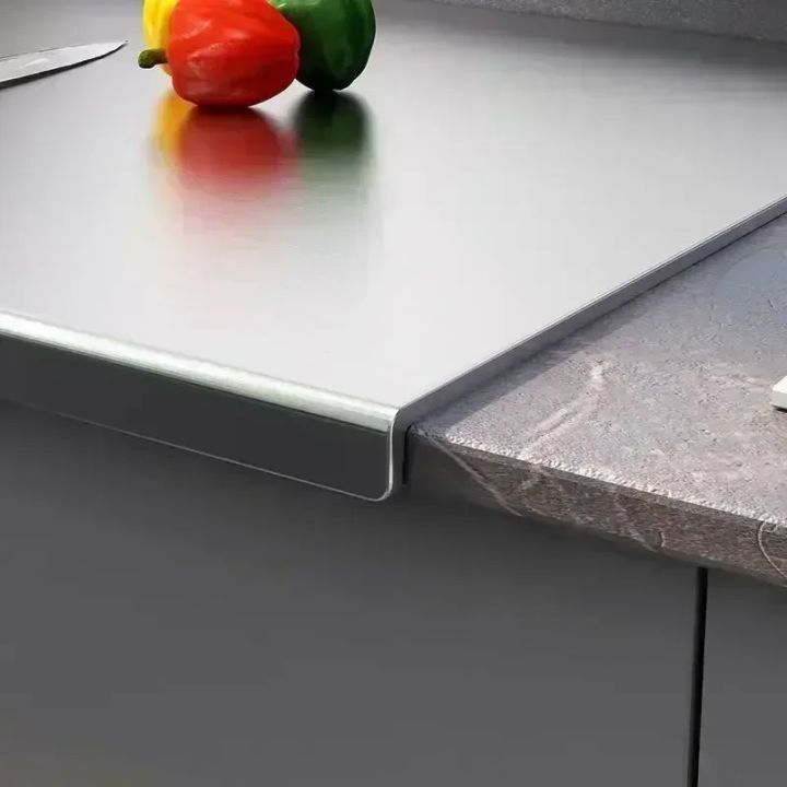 Non-slip folded lip edge of titanium cutting board gripping kitchen countertop