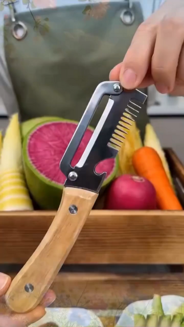 3-in-1 stainless steel peeler with wooden handle held in hand — wide curved blade with julienne teeth