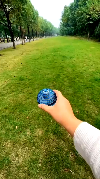 Blue flying ball toy held in hand outdoors ready to fly
