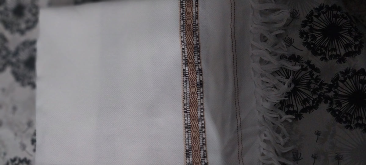 White shawl edge detail — woven border band with loose fringe tassels