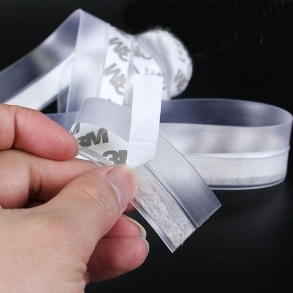 Close-up of hand peeling the 3M adhesive backing off the transparent silicone window sealing tape