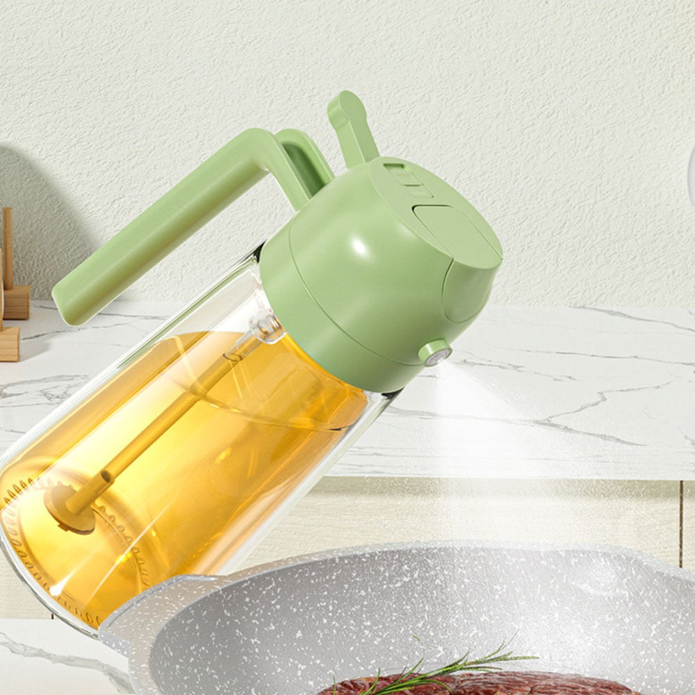 Olive oil sprayer spraying a fine mist over a pan, green press top and side handle