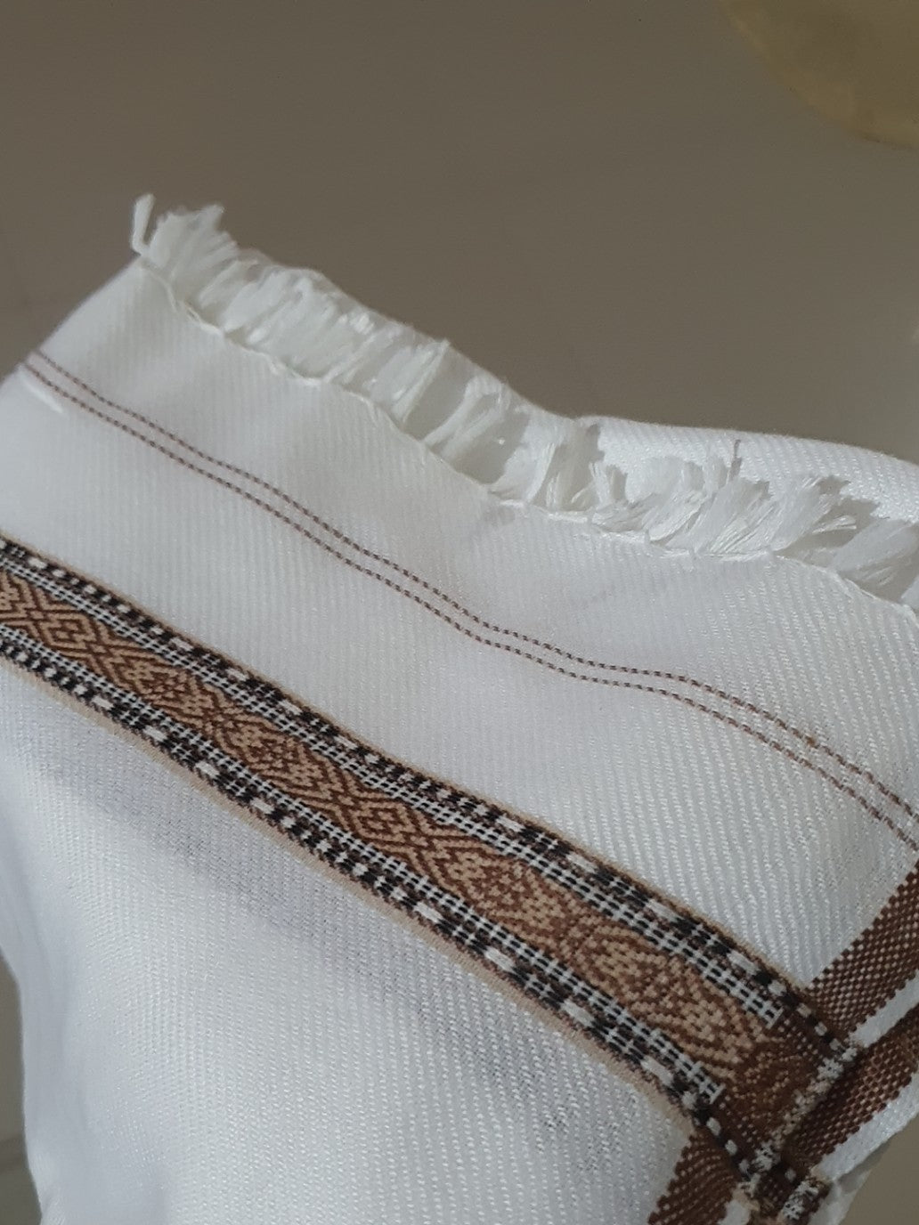 Close-up of the shawl's fringed edge and woven brown-gold border detail