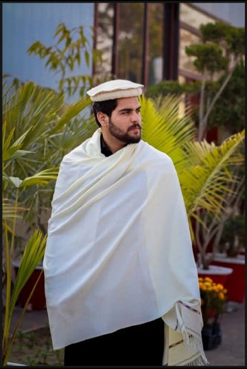 Model wearing the white woolen men's winter shawl draped over the shoulders outdoors — fringed edges visible