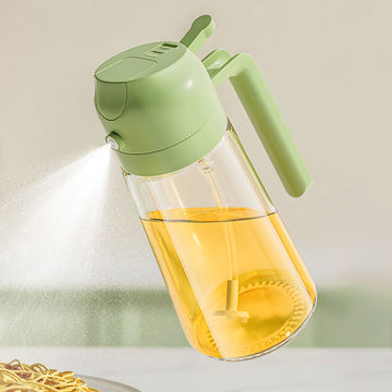 Olive oil sprayer spraying a fine mist over food, green press top and clear glass bottle